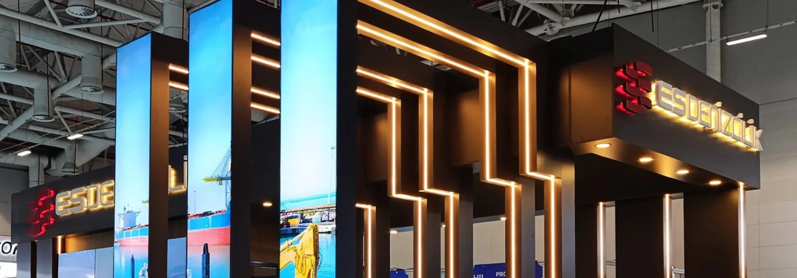 Es Denizcilik için kurulmuş fuar standı; ışıklı kumaş paneller, gizli LED şeritler ve markalı alınlık görünüyor.